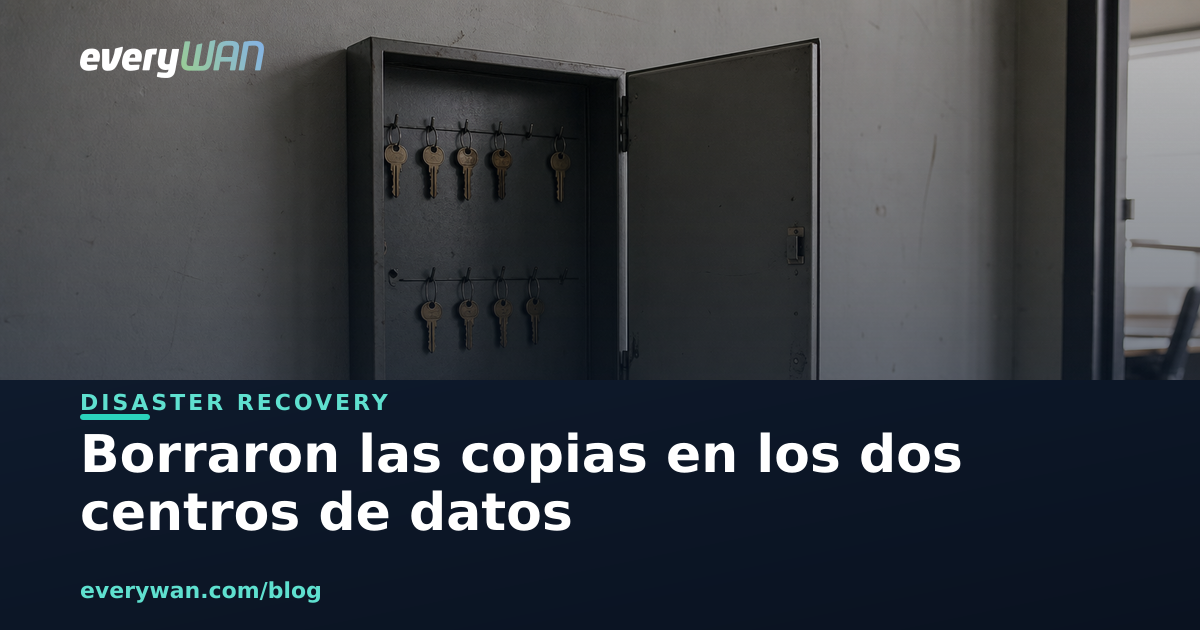Armario de llaves metálico abierto en el pasillo de servicio de una oficina, con dos hileras de llaves colgadas de sus ganchos