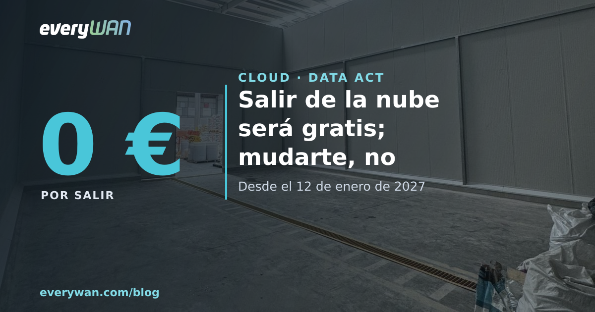 Nave industrial vacía con el suelo de hormigón, un palé en primer plano y la puerta abierta al fondo