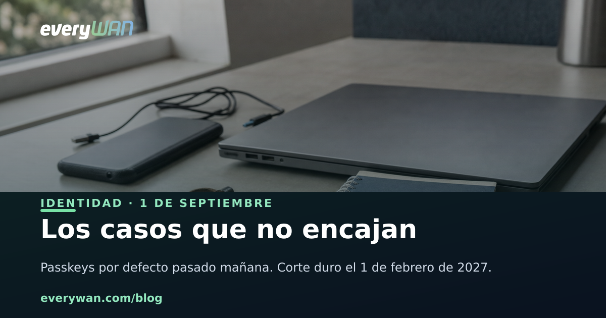 Mesa de oficina con un portátil cerrado, una llave de seguridad USB en un llavero y un teléfono móvil boca abajo